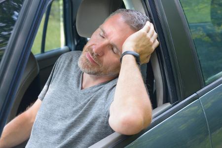 Ein Mann, der genervt die Augen schließt, im Auto sitzend Ein Mann, der genervt die Augen schließt, im Auto sitzend
