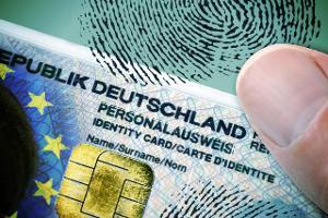 FOTOMONTAGE, Finger auf deutschem Personalausweis mit EU-Fah...