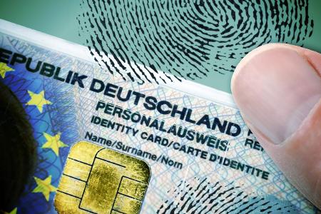 FOTOMONTAGE, Finger auf deutschem Personalausweis mit EU-Fah...