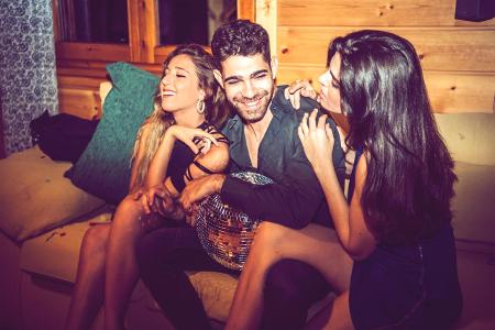Flirt-Mythen Young women flirting with man while sitting with him on sofa... Flirt-Mythen Young women flirting with man while sitting with him on sofa...