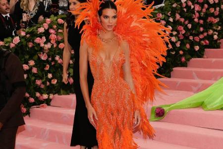 Kendall Jenner erschien in einer orangfarbenen Feder-Robe von Versace. Das enganliegende Kleid brachte ihre Figur bestens zu...