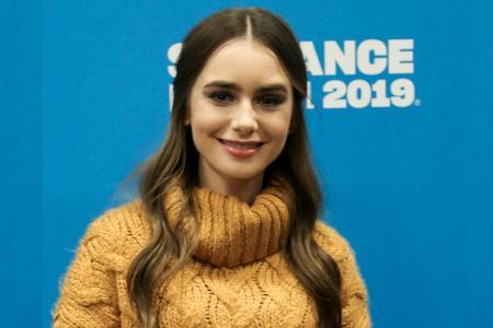 Schauspielerin Lily Collins strahlt im senfgelben Strickpullover. Schauspielerin Lily Collins strahlt im senfgelben Strickpullover.