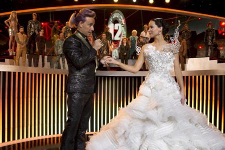 Moderator Caesar Flickerman (Stanley Tucci) ahnt nicht, dass sich unter Katniss' (Jennifer Lawrence) Brautkleid ein schwarze... Moderator Caesar Flickerman (Stanley Tucci) ahnt nicht, dass sich unter Katniss' (Jennifer Lawrence) Brautkleid ein schwarze...