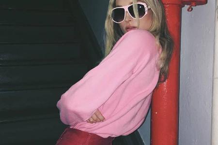 Sonnenbrille und Pulli in Pink, die Hose in der Signalfarbe Rot. Selbst die Rohrleitung passt farblich zu Model Elsa Hosk