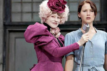 Katniss (Jennifer Lawrence, r.) meldet sich freiwillig für die Arena. Moderatorin und Betreuerin Effie Trinket (Elizabeth Ba... Katniss (Jennifer Lawrence, r.) meldet sich freiwillig für die Arena. Moderatorin und Betreuerin Effie Trinket (Elizabeth Ba...