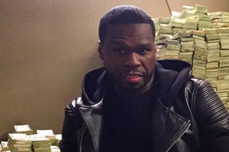 50 Cent sitzt lässig vor einem Berg aus Geldscheinen. 50 Cent sitzt lässig vor einem Berg aus Geldscheinen.