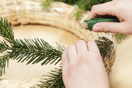 Für den klassischen Adventskranz brauchen wir einen Strohkranz, Tannenzweige, grünen Draht und etwas Geschick.