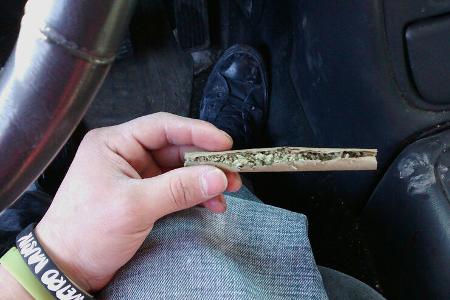 Mann baut Joint im Auto.