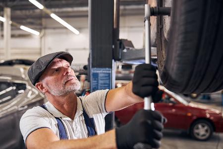 Bearded,Man,In,Gloves,Tightening,Bolts,On,Wheel,With,Torque