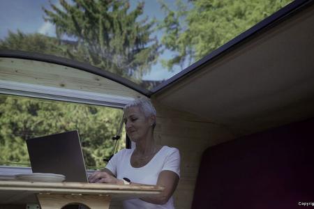Eine Frau sitzt im Inneren des Free Chilli an einem Tisch und arbeitet mit ihrem Laptop.