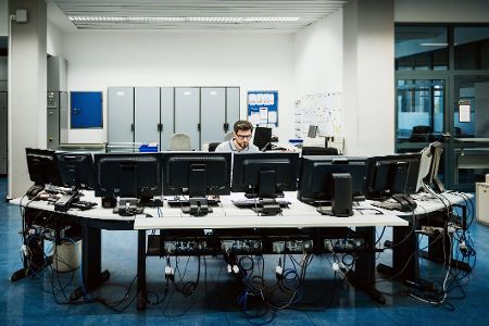 Mann in einem Überwachungszentrum vor Monitoren