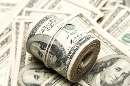 Zusammengerollte Dollarscheine liegen auf weiteren Dollarscheinen