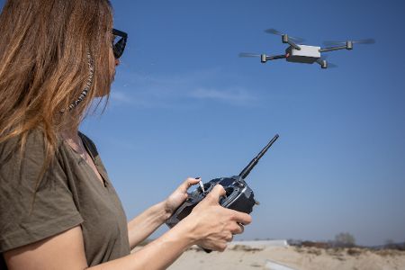 Frau mit Fernbedienung in der Hand steuert eine Drohne