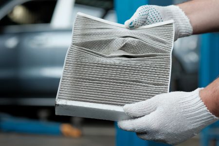 Hände mit Latexhandschuhen halten einen Filter in Laboratmosphäre