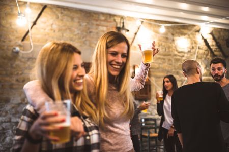 Zwei Frauen feiern, im Hintergrund sind Männer zu sehen