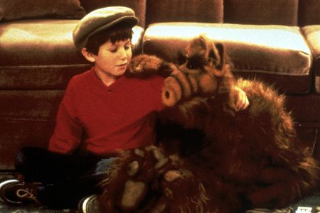 Kleiner Junge sitzt mit lebensgroßer Puppe auf dem Boden vor einer Couch