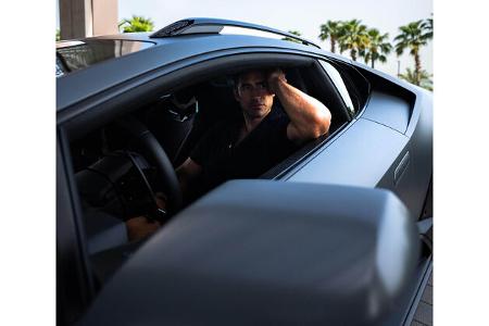 Mann präsentiert Modekollektion von Lamborghini und Orlebar Brown.