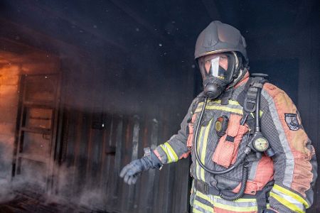 Ein Proband mit einem Prototyp einer intelligenten Feuerwehrjacke am Weg in die Brandsimulationsanlage