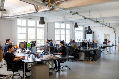 Großraumbüro mit vielen Menschen, die an Rechnern arbeiten