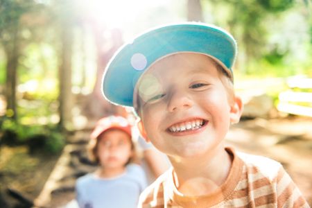Kinder in einem Wald, wo die Sonne durch die Bäume scheint