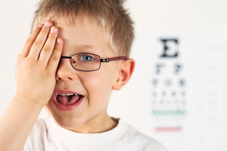 Junge hält sich ein Auge zu und macht einen Sehtest