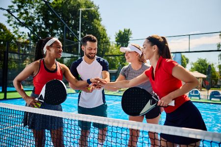 Vier Padel-Tennisspieler stehen gemeinsam am Netz Vier Padel-Tennisspieler stehen gemeinsam am Netz