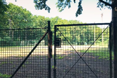 Verwachsener Fußballplatz hinter einem verschlossenen Tor