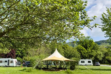 Ein Campingplatz unter dem Berg Jenzig bei Jena mit mehreren Zelten und Wohnwagen. 