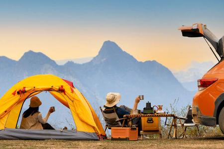 Campingszene mit orangener Zeltmontur und Carcamper Campingszene mit orangener Zeltmontur und Carcamper