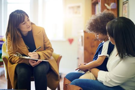 Psychologin spricht mit Kleinkind und dessen Mutter