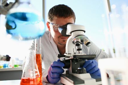 Virologe untersucht etwas im Mikroskop
