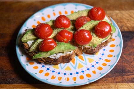 Eine Scheibe Kürbiskernbrot mit Avocado und Tomaten. Viele jüngere Leute in Deutschland sehen sich eher als Avocadobrot- denn Wurstbrot-Typ. (Symbolbild)