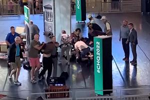 Menschen kümmern sich um den verletzten Rushdie, während ein Mann von der Bühne eskortiert wird. (Aufnahme kurz nach dem Angriff)