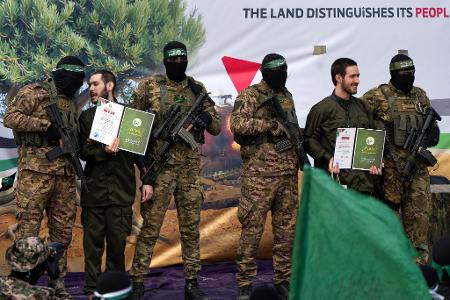 Ein vermummter Hamas-Kämpfer gibt einer israelischen Geisel Anweisungen während einer Übergabe-Veranstaltung im Gazastreifen.