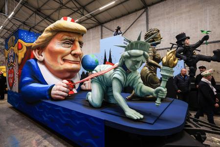 Einer der Wagen im Kölner Rosenmontagszug zeigt US-Präsident Donald Trump, der die Freiheitsstatue und die Justitia am Laufband führt.
