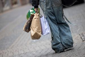 Eine Passantin geht mit Tragetaschen durch eine Einkaufstraße in Köln.