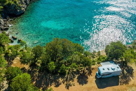Luftaufnahme des malerischen Wohnmobil-Campingplatzes am Meer. Modernes Wohnmobil Van am Mittelmeer Kroatische Küste. Urlaub unterwegs. Türkisfarbene Bucht. 