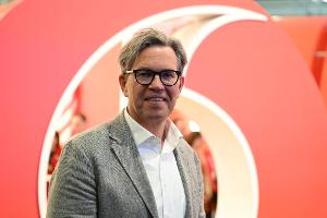 Vodafone-Deutschlandchef Marcel de Groot vor einem großen Plastik-Logo seiner Firma.