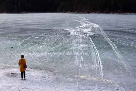 Eine Frau steht am Ufer des zugefrorenen Eibsees, nahe der Stelle an der am Nachmittag mehrere Menschen im Eis eingebrochen waren. Eine Frau steht am Ufer des zugefrorenen Eibsees, nahe der Stelle an der am Nachmittag mehrere Menschen im Eis eingebrochen waren.