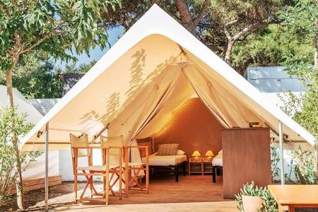Glamping open tent with cozy interior on a sunny day. Luxury camping tent for outdoor summer holiday and vacation. Lifestyle concept