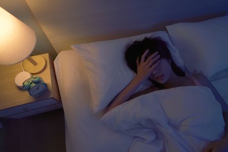 Frau liegt nachts wach im Bett