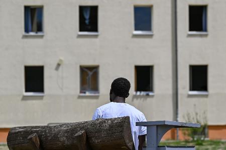 Ein Migrant sitzt auf einer Bank auf dem Gelände der Zentralen Erstaufnahmeeinrichtung für Asylbewerber des Landes Brandenburg in Eisenhüttenstadt. (Archivfoto)