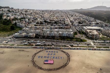 An einem Strand im Bundesstaat Kalifornien bildeten Demonstranten einen menschlichen Kreis um eine US-Flagge und den Slogan 
