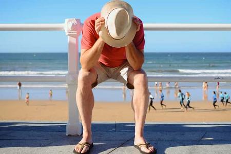 Symbolbild: Mann sitzt frustriert am Strand Symbolbild: Mann sitzt frustriert am Strand