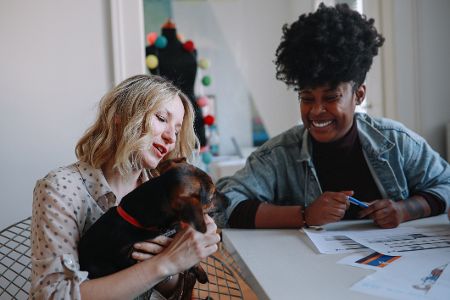 Behördenmitarbeiterin beobachtet Frau, die einen Hund auf dem Schoß hat