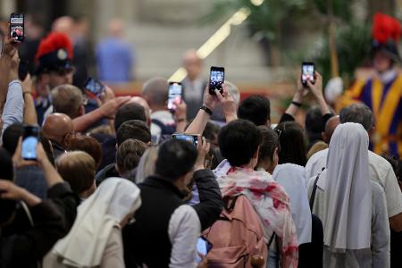 Mit den Smartphones machen Gläubige ein Foto vom toten Papst.