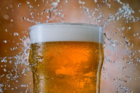 Gefülltes Bierglas aus dem Wasser und Schaum spritzt