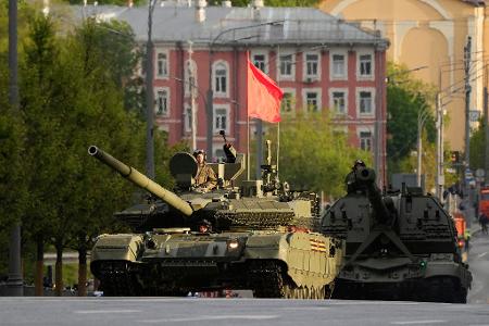 Ein russischer Panzer und eine Panzerhaubitze rollen auf einer Straße in Richtung Roter Platz, um an einer Probe für die Militärparade zum Tag des Sieges teilzunehmen.