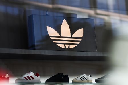 Logo von Adidas über einer Reihen von Sportschuhen in einem Laden