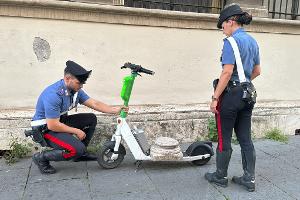 Zwei Carabinieri begutachten den Marmorsockel auf einem elektrischen Leihroller.